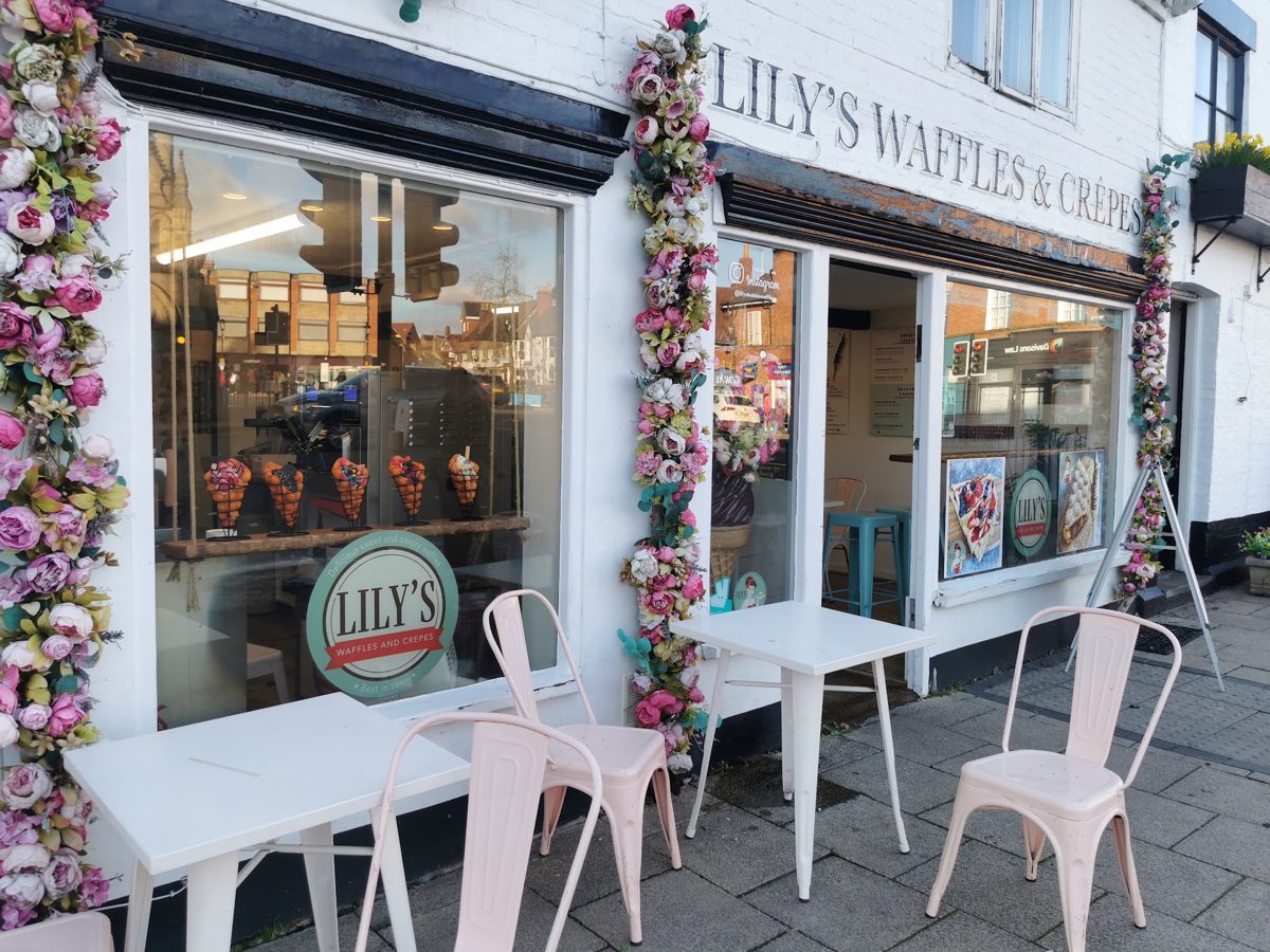 The white shopfront with LILY’S WAFFLES & CRÊPES lettering, flowers and outdoor chairs
