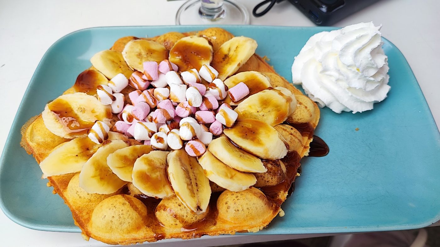 A waffle with banana, marshmallows and cream
